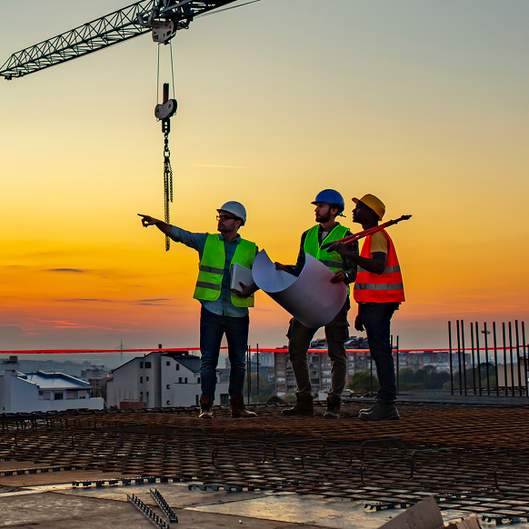 Three construction workers on top of a building under construction